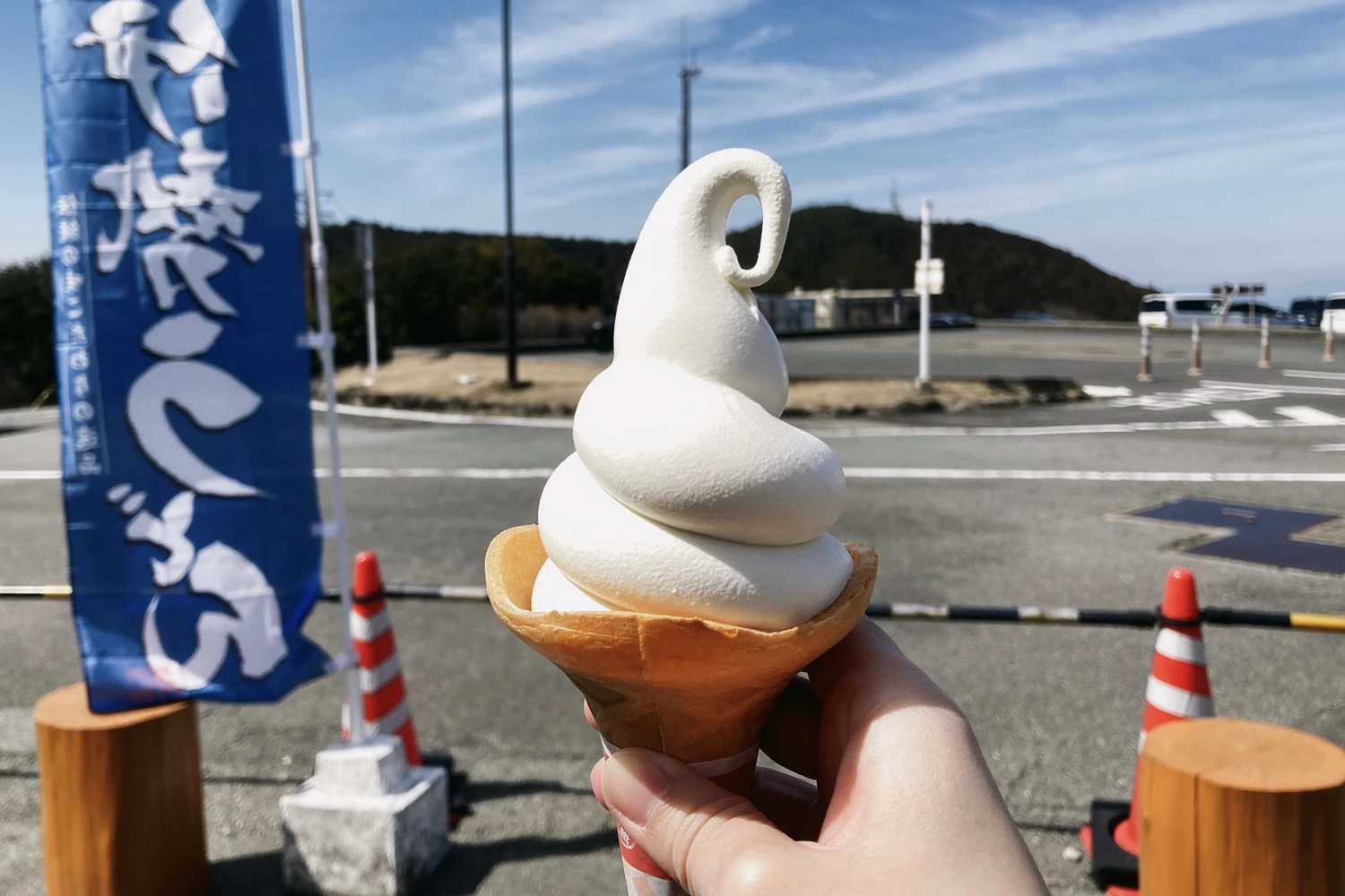 white soft serve in a wafer cone, the vast sky above