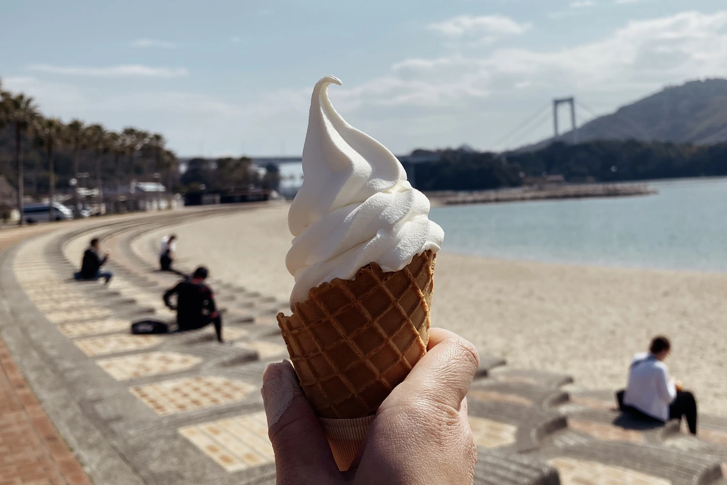 white soft serve in a waffle cone, on a beach