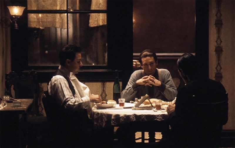 screenshot from the film 'the godfather part 2'. three guys are having dinner together at home.