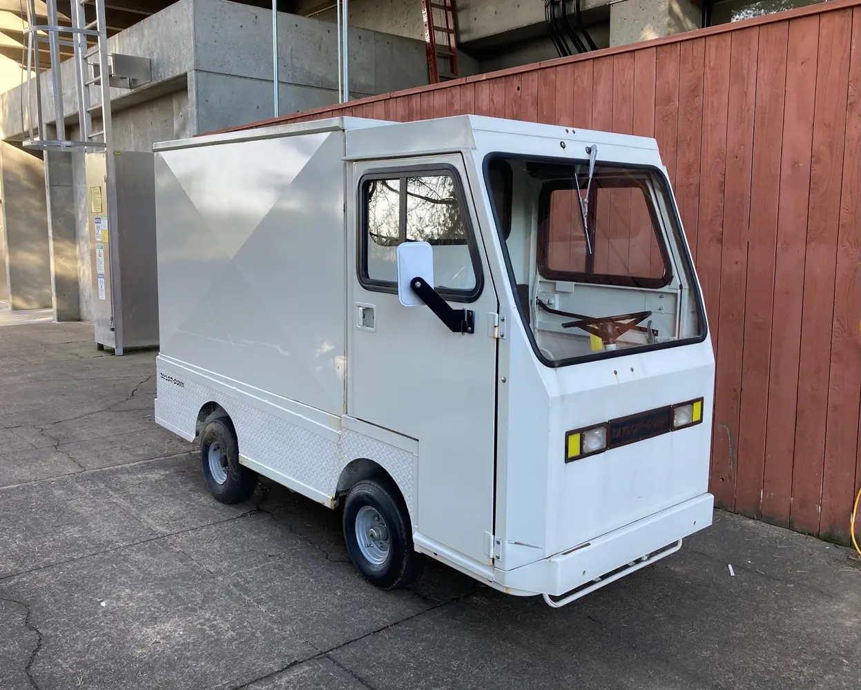 a very small, boxy white car with only one seat. it's probably only used around a small area for transporting small things